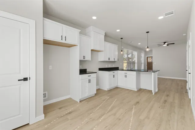 a open kitchen with white cabinets and wooden floor