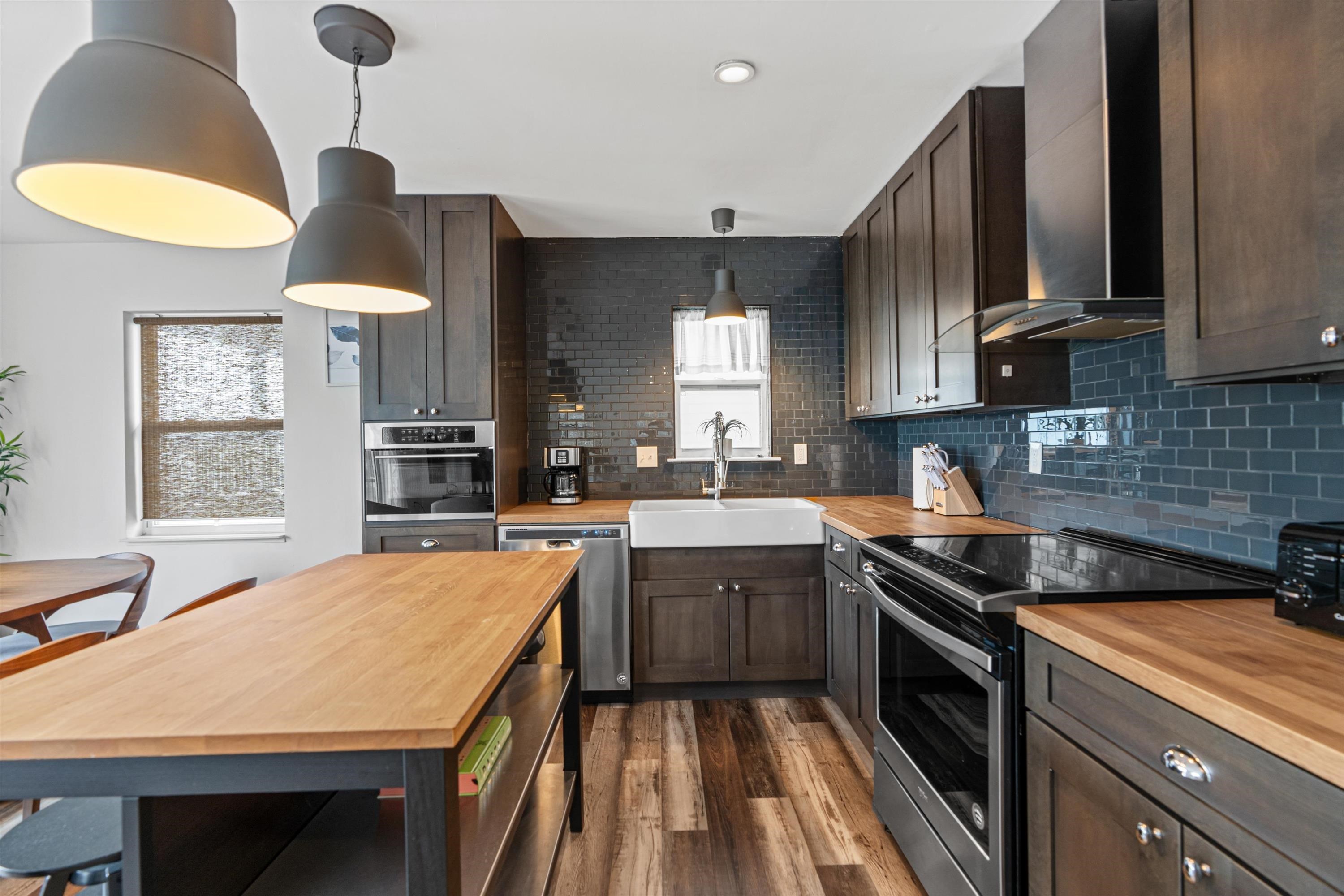 9 3rd Street, Unit UP St. Augustine, FL 32080 - Photo 7 of 24 a kitchen with stainless steel appliances granite countertop a sink a stove and a wooden floors