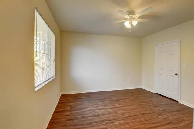 a view of an empty room with wooden floor and a window
