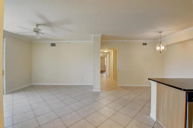 a view of an empty room and chandelier fan