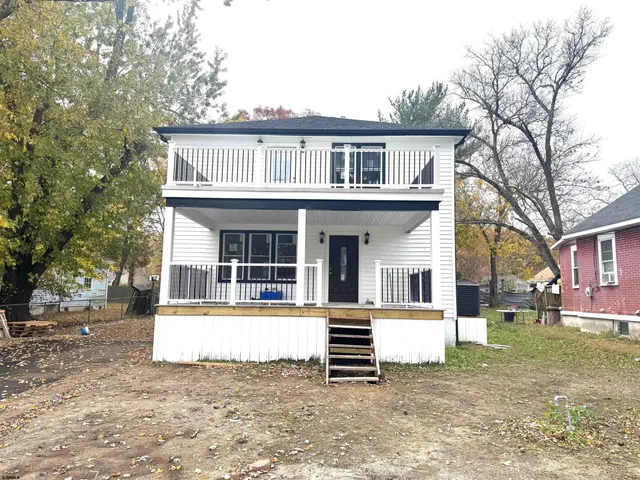 a view of a white house with large windows and a yard with palm trees