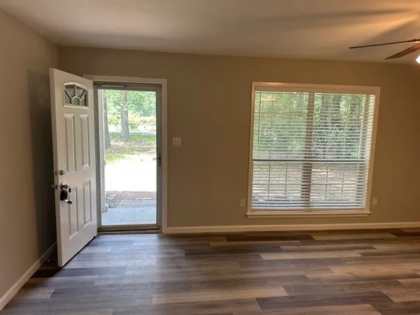 a view of an empty room with wooden floor and a window