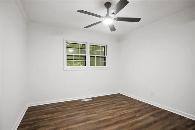 an empty room with wooden floor chandelier fan and windows
