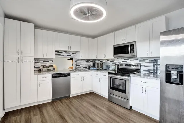 a kitchen with cabinets stainless steel appliances and wooden floor