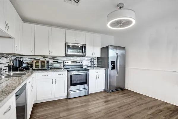 a kitchen with granite countertop a refrigerator stove and sink