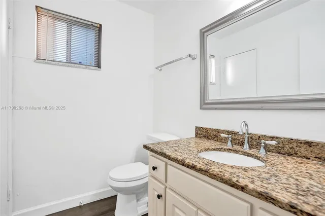 a bathroom with a granite countertop sink and a toilet