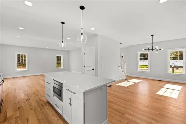 a large kitchen with kitchen island a stove a sink a center island and wooden floor
