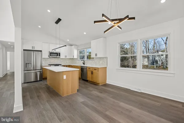 a kitchen with a refrigerator a sink dishwasher with a stove and white cabinets with wooden floor