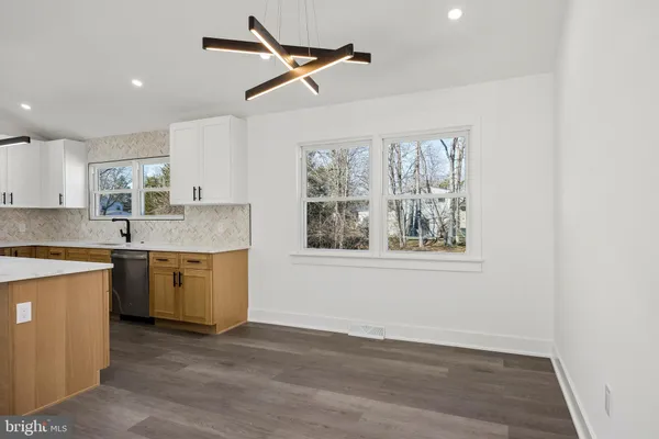 a kitchen with granite countertop a stove a sink and white cabinets with wooden floor next to windows