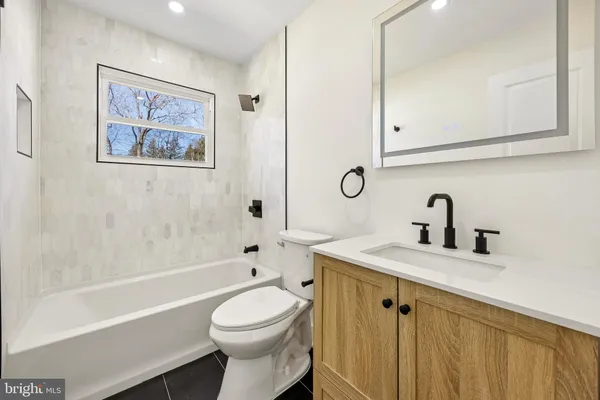 a bathroom with a granite countertop sink mirror vanity and toilet