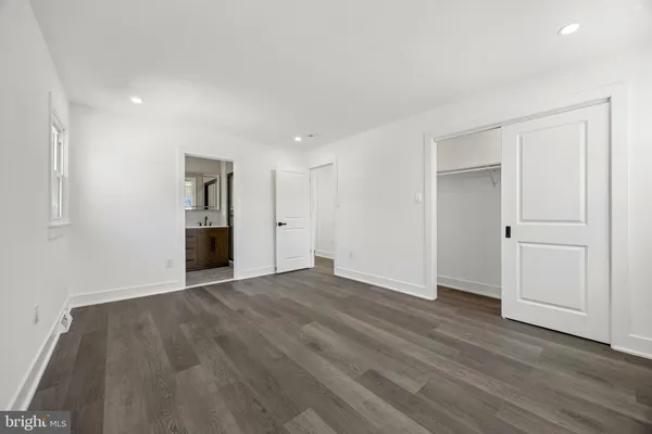 a view of an empty room with wooden floor and closet