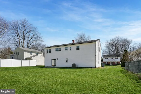 a view of a white house with a big yard and large trees