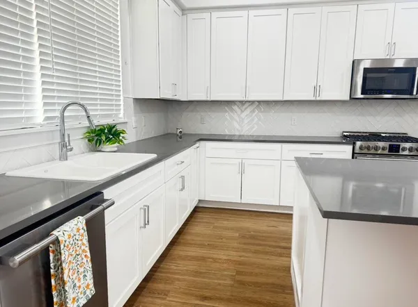 a kitchen with granite countertop a sink a stove and cabinets