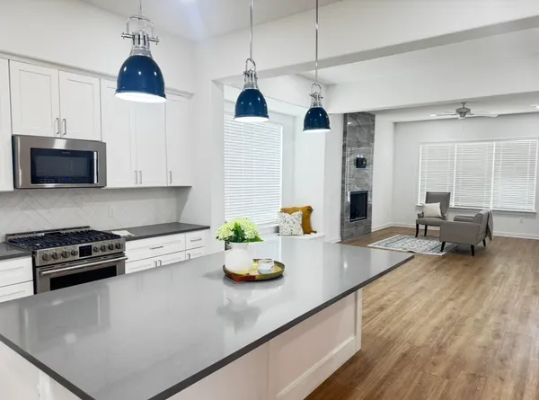 a kitchen with stainless steel appliances granite countertop a sink dishwasher and a refrigerator with wooden floor