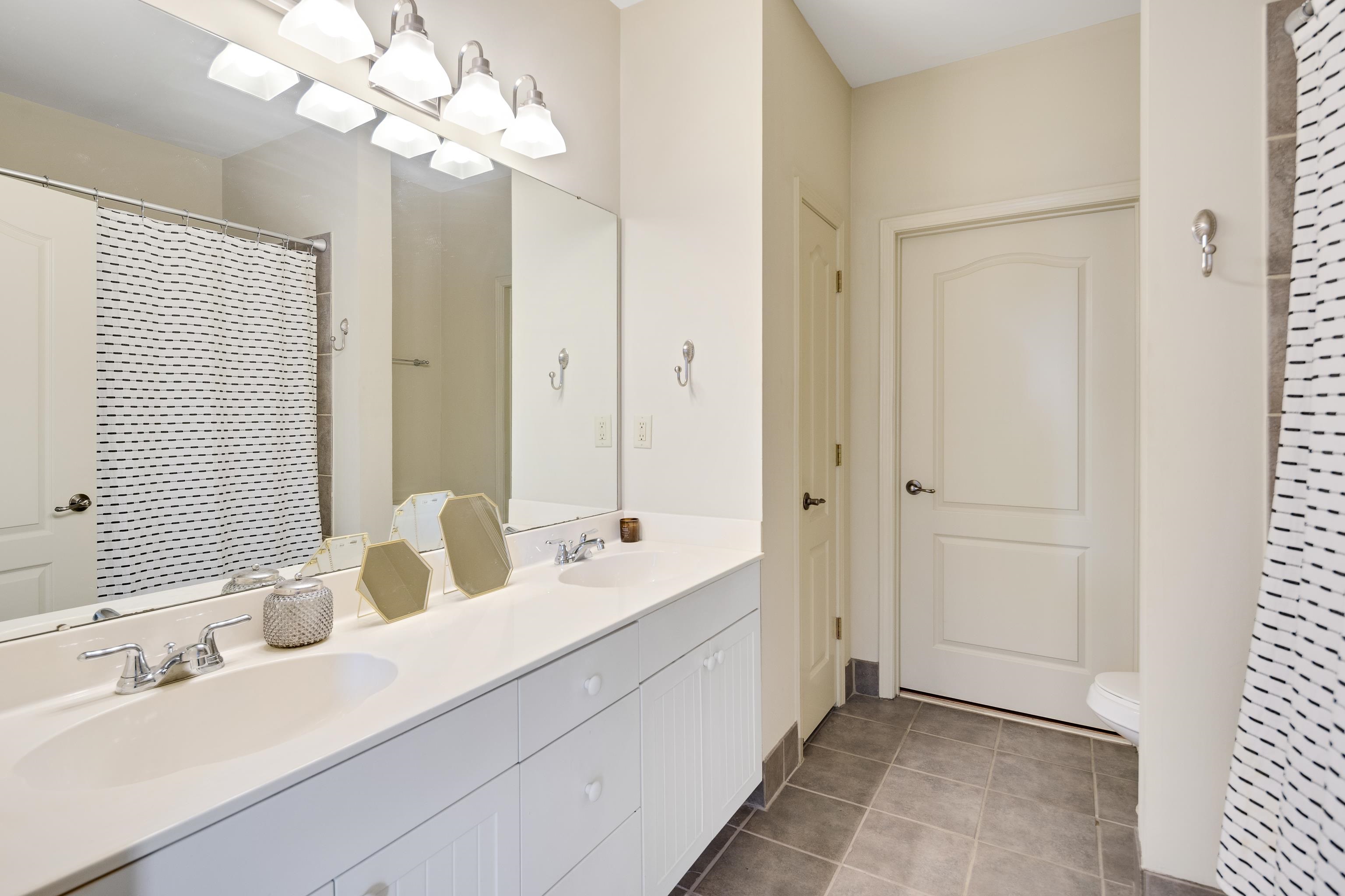 600 South Main Street, Unit 101 Memphis, TN 38103 - Photo 21 of 35 a en suite bathroom with a double vanity sink mirror and chandelier