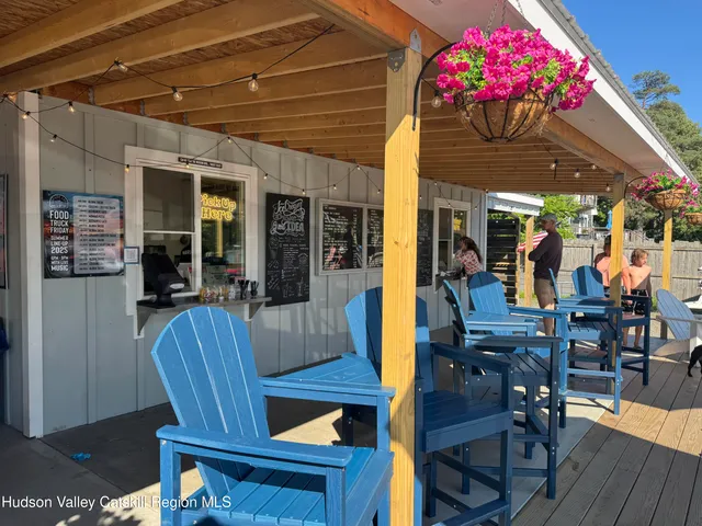 a view of a patio with table and chairs under an umbrella with a barbeque