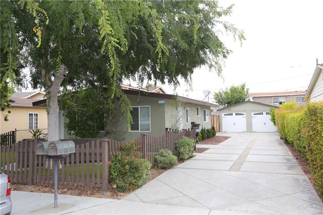 a front view of a house with a yard and potted plants