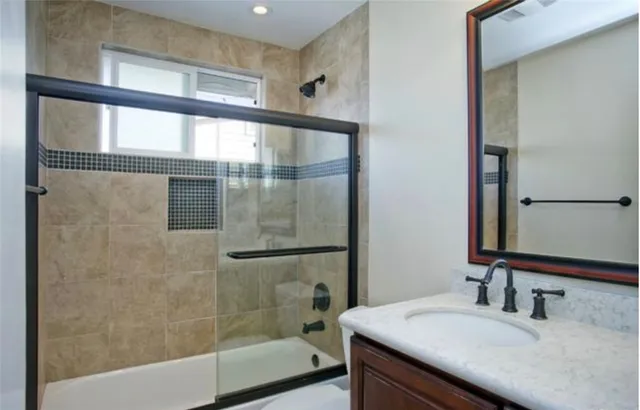 a bathroom with a granite countertop sink mirror and a bathtub