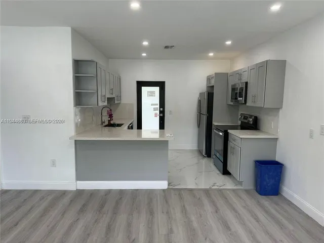 a large kitchen with kitchen island a sink stainless steel appliances and cabinets