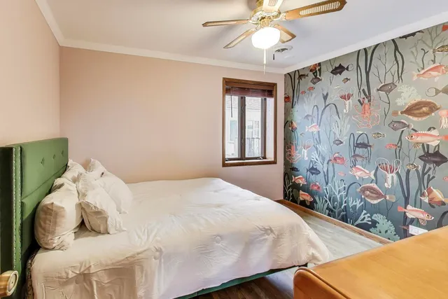 a bed sitting in a bedroom next to a window and a chandelier