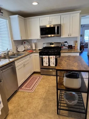 a kitchen with granite countertop a stove a sink and a microwave