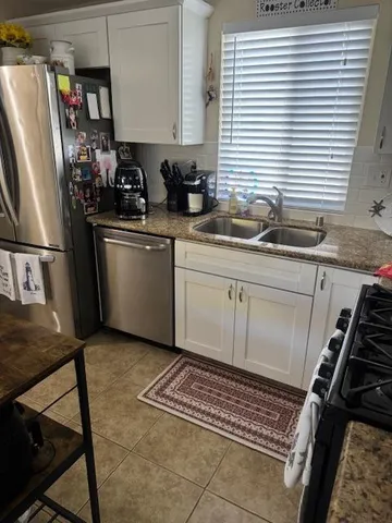 a kitchen with a sink appliances cabinets and a window