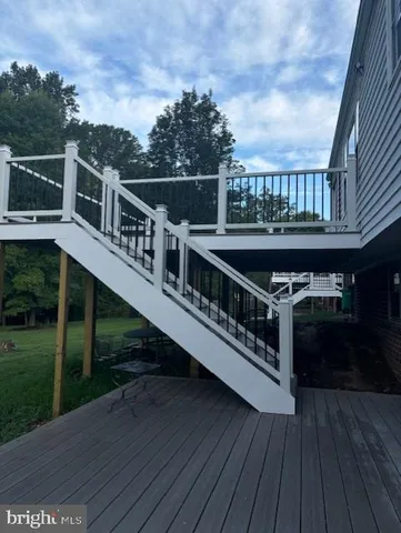 a balcony with wooden floor outdoor seating and yard in the back