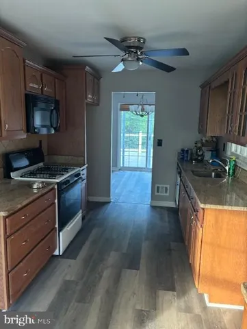 a kitchen with granite countertop a stove a sink and a refrigerator