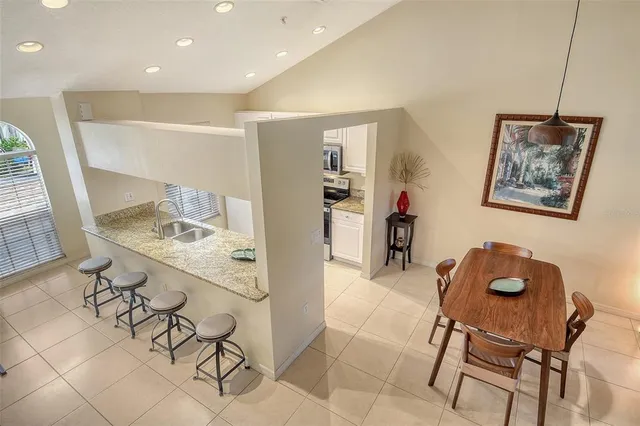 a dining hall with stainless steel appliances granite countertop a stove a sink a dining table and chairs