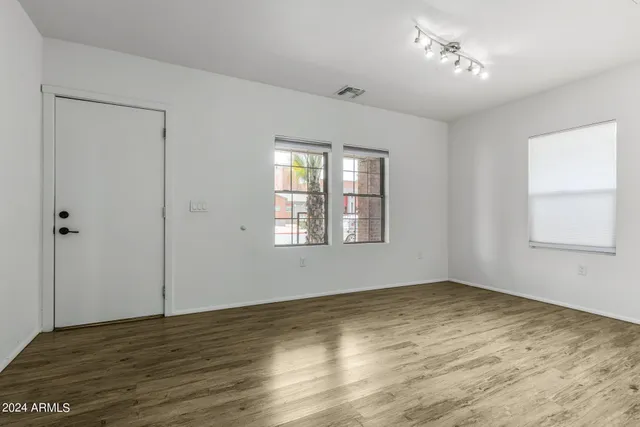a view of an empty room with wooden floor and a window