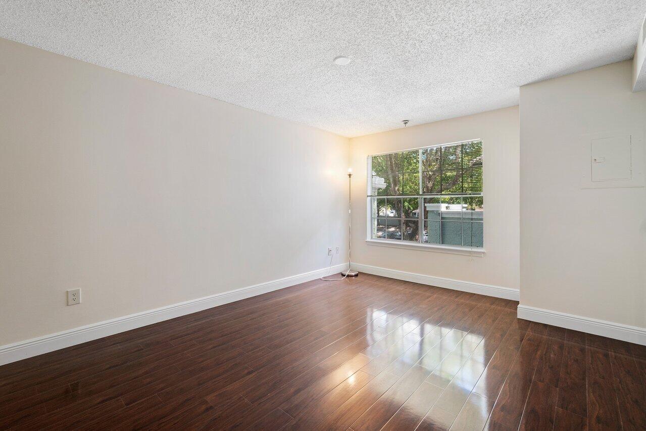 1275 Crystal Way, Unit B Delray Beach, FL 33444 - Photo 20 of 37 a view of an empty room with wooden floor and a window