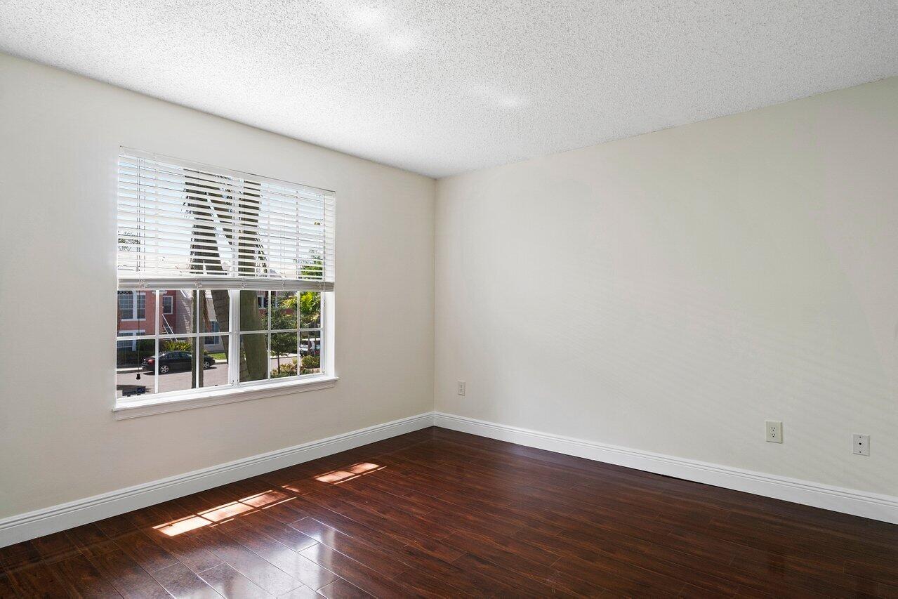 1275 Crystal Way, Unit B Delray Beach, FL 33444 - Photo 23 of 37 a view of an empty room with wooden floor and a window
