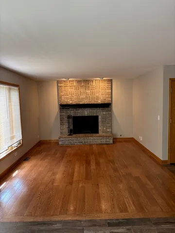 a view of empty room with wooden floor and fireplace
