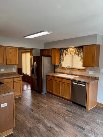 a kitchen with stainless steel appliances granite countertop a refrigerator a sink dishwasher a stove and white countertops with wooden floor