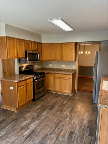 a kitchen with granite countertop a refrigerator a stove top oven a sink and dishwasher