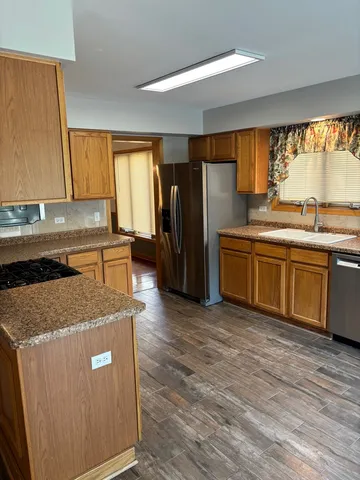 a kitchen with stainless steel appliances granite countertop a sink a refrigerator and a stove top oven
