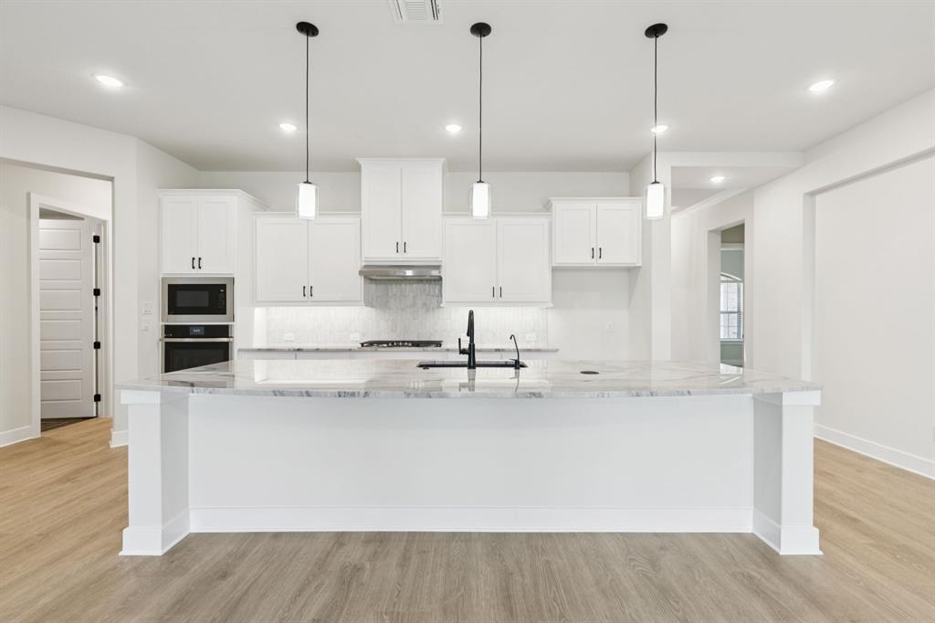 224 Bee Balm Road McKinney, TX 75071 - Photo 4 of 20 a large kitchen with stainless steel appliances kitchen island a large counter top and a wooden floors