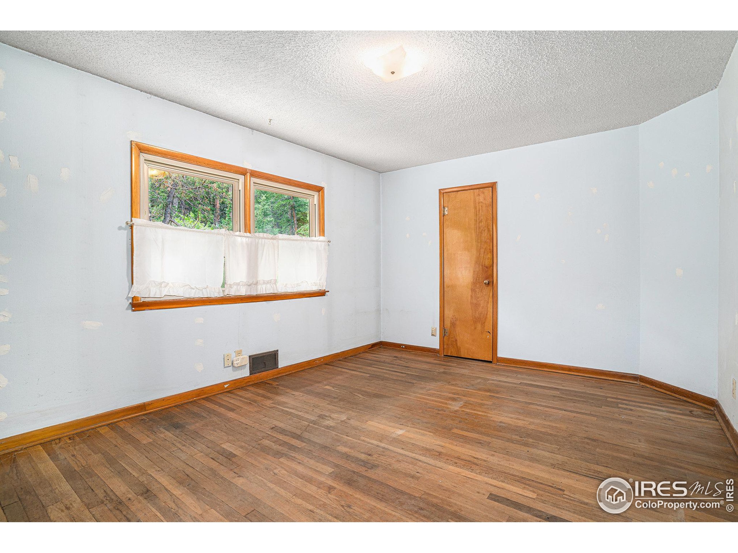 143 Waltonia Road Drake, CO 80515 - Photo 14 of 30 a view of an empty room with wooden floor and a window