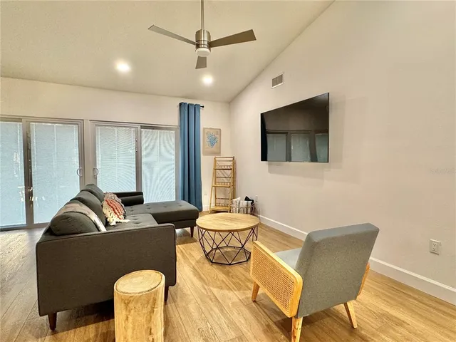 a living room with furniture a flat screen tv and wooden floor