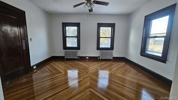 a view of empty room with wooden floor and fan