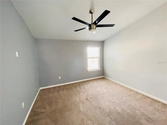 an empty room with ceiling fan and window