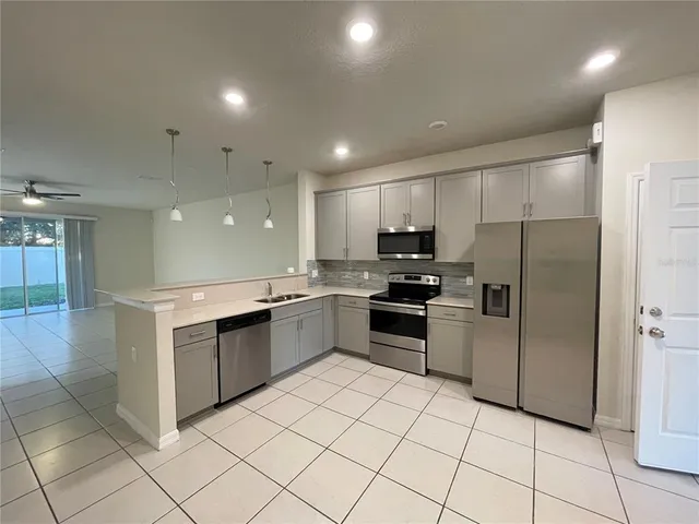 a kitchen with stainless steel appliances kitchen island granite countertop a refrigerator and a sink