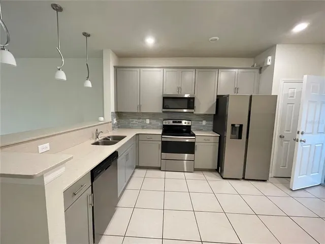 a kitchen with a sink a refrigerator and a stove top oven