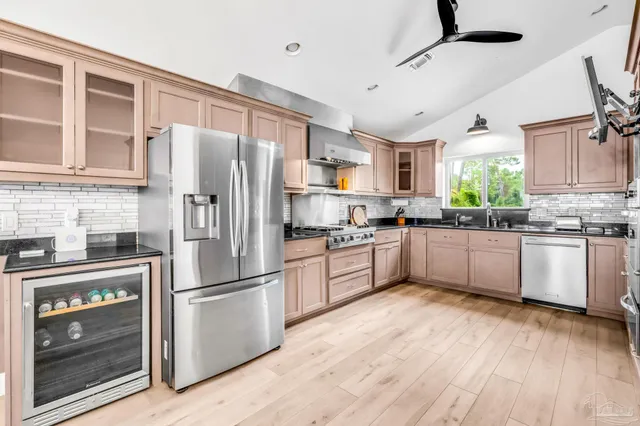 a kitchen with granite countertop a refrigerator oven a sink dishwasher and white cabinets with wooden floor