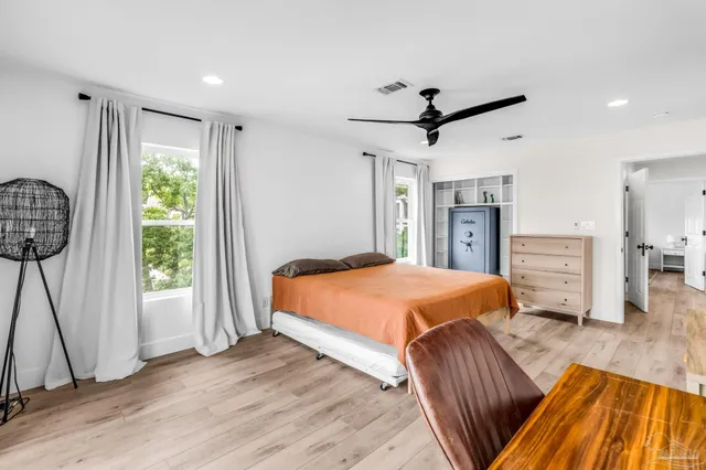 a spacious bedroom with a bed a dresser and a chandelier