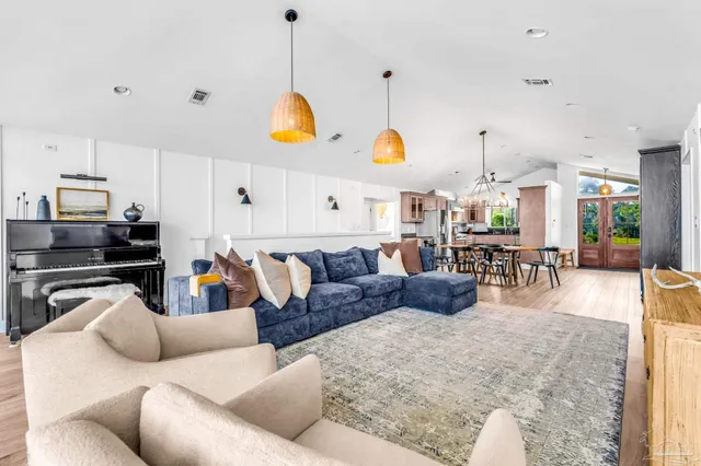 a living room with furniture kitchen view and a wooden floor