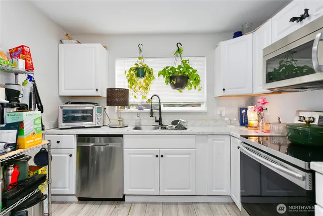 a kitchen with granite countertop a sink stainless steel appliances and cabinets