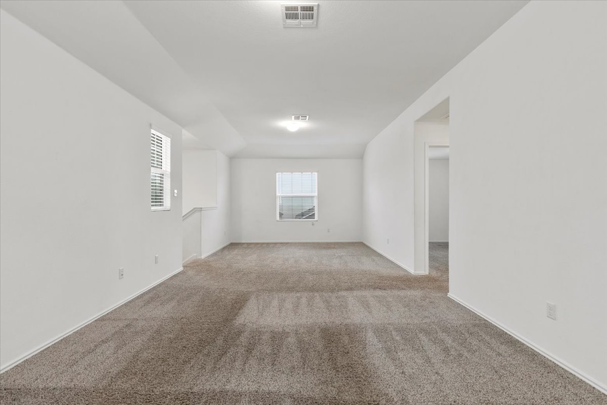 101 Rowdy Yates Way Jarrell, TX 76537 - Photo 13 of 32 Spacious room featuring neutral carpet flooring, white walls, and multiple windows with blinds