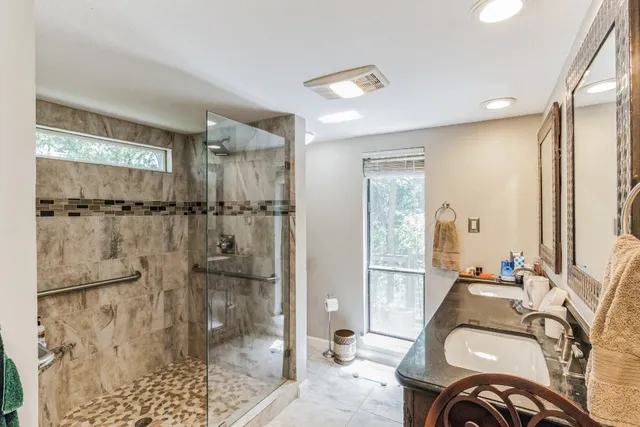 a bathroom with a granite countertop shower a mirror and a sink