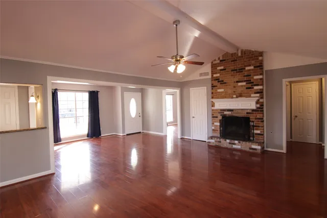 a view of an empty room with wooden floor fireplace and a window